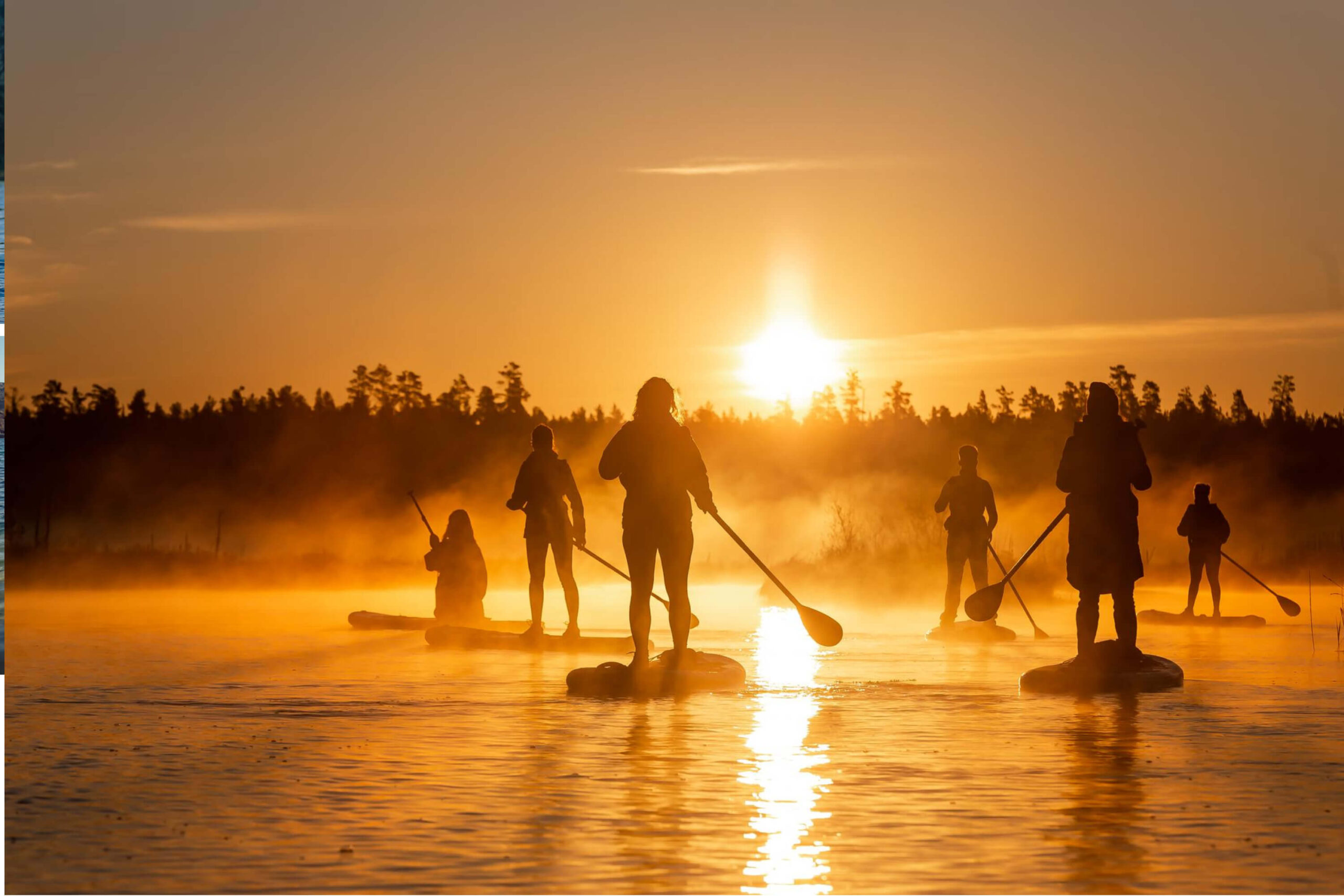 A group of paddleboarders, lit by the stting sun bathed in mist